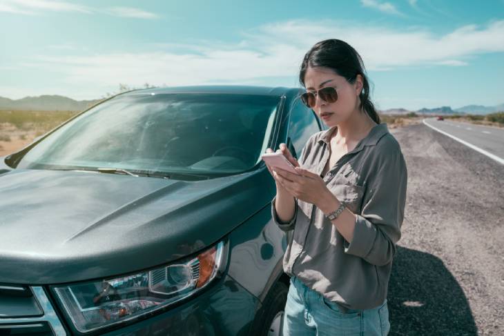 Photo of girl standing next to car with phone in hand