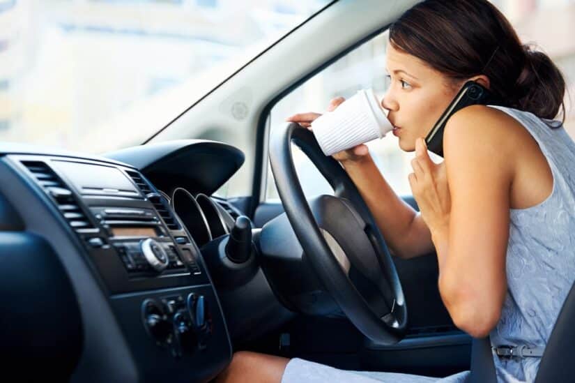 Woman Drinking Coffee And Talking On The Phone While Driving