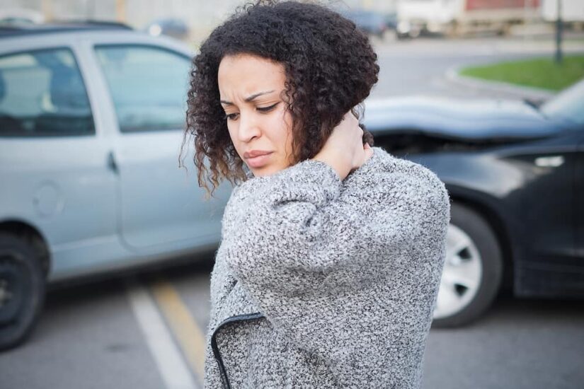 Car Accident Woman Holding Her nEck In Pain Next To A Car Crash Scene
